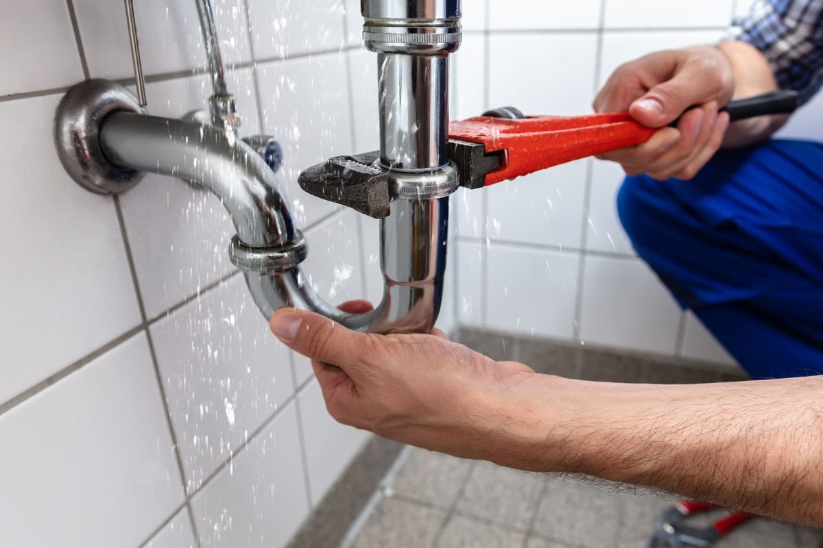 Plombier réparant le siphon d'un lavabo à la clé